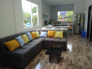 uma sala de estar com um sofá preto com almofadas amarelas em Departamento cómodo vacacional em Manta