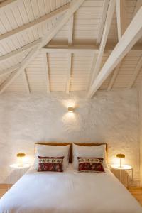 a bedroom with a large white bed with two lamps at Casas do Capitão - Paiva Valley - Pool and Nature in Castelo de Paiva +62 photos