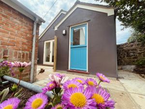 ein Haus mit einer blauen Tür und lila Blumen in der Unterkunft The Garden House in Penzance