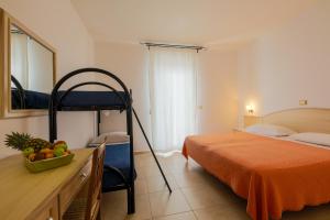 a bedroom with a bed and a desk with a bowl of fruit at Hotel Corallo in Torre Santa Sabina