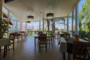 a restaurant with tables and chairs and windows at Hotel Corallo in Torre Santa Sabina