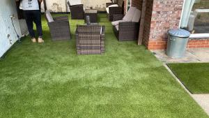 a patio with green grass and chairs and a person at Hotel in Harrow