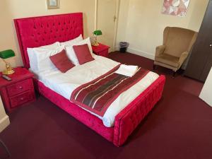 a bedroom with a large bed with a red headboard at Hotel in Harrow