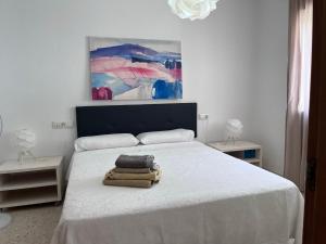 sypialnia z białym łóżkiem i obrazem na ścianie w obiekcie Apartamento céntrico en Tarifa. w mieście Tarifa