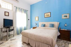 a blue bedroom with a bed and a television at L'Isola Di Ortigia in Syracuse
