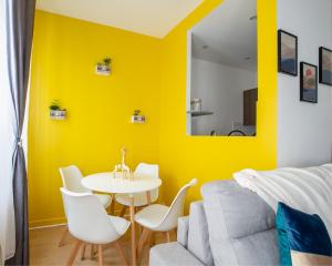 ein gelbes Wohnzimmer mit einem weißen Tisch und Stühlen in der Unterkunft Le Marché de l'Elégance à Vernon-Giverny - Claude Monet - Downtown in Vernon