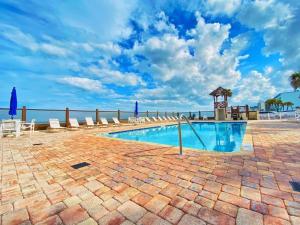 a swimming pool with chairs and the ocean in the background at Sea Dip Resort Studios! in Daytona Beach