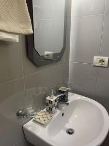 lavabo blanco en el baño con espejo en Ona's House, en Borsh