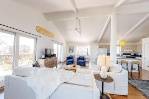 a living room with white furniture and a kitchen at Sand Shack in Frisco