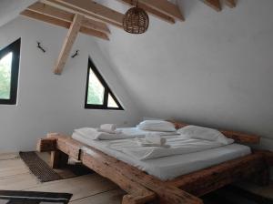una camera da letto con letto in legno, lenzuola e cuscini bianchi di Casa Nectaria a Moieciu de Jos