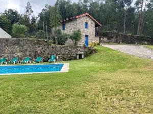 uma casa de pedra com cadeiras e uma piscina em Quinta Gerês em Terras de Bouro