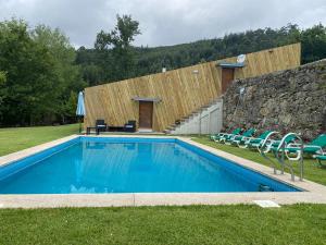 a swimming pool with chairs and a stone wall at Quinta Gerês in Terras de Bouro