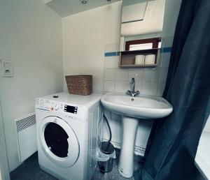 Un baño con lavadora y lavabo. en Le Sacré, Au pied de la cathédrale, en Reims