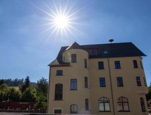 a large building with the sun in the sky at Wurzelrudis Hostel in Eibenstock