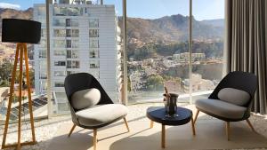two chairs and a table in front of a large window at Onkel Inn Apart Suites in La Paz