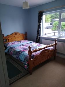 a bedroom with a wooden bed and a window at Cub Cottage in Kilcoo