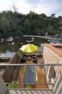 eine Terrasse mit einem gelben Regenschirm und einem Fluss in der Unterkunft Gîte proche Puy du Fou in Mortagne-sur-Sèvre