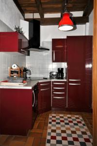 Mortagne-sur-SèvreにあるGîte proche Puy du Fouの赤いキャビネットと赤いランプ付きのキッチン