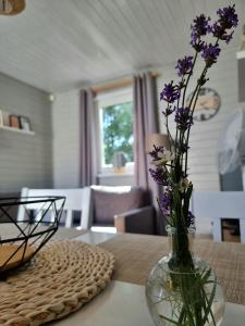 wazon z fioletowymi kwiatami na stole w obiekcie Domki z jacuzzi nad zatoką w mieście Puck