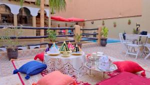 stół z kapeluszami, krzesłami i basenem w obiekcie Riad Benyara w mieście Tarudant