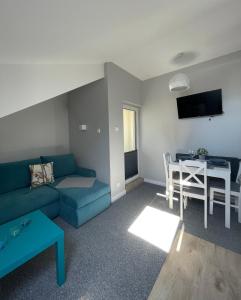uma sala de estar com um sofá azul e uma mesa em Apartamenty i Pokoje Atlantic em Jastrzębia Góra
