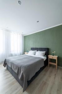 een slaapkamer met een groot bed met een groene muur bij Apartaments Nr.33 (Viesu Nr.3) in Talsi