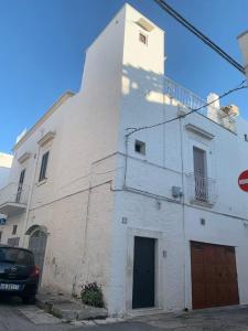 a white building with a car parked in front of it at Casa Sunshine in Ostuni