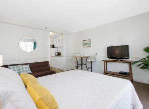 a bedroom with a white bed and a television at Vacation Apartment for Couples in Honolulu Hawaii in Honolulu