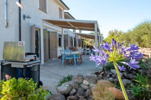 a patio with a table and a purple flower at Lu Casal de Fiò in Alghero +48 photos
