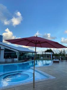 um guarda-chuva vermelho sentado ao lado de uma piscina em Casa Alto do Cunhau em Barra do Cunhau