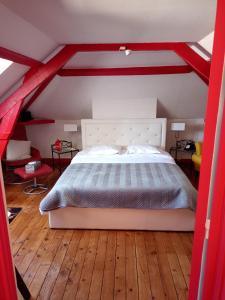 een rood en wit bed in een kamer met houten vloeren bij La Cour Du Puits Chambre Victor in Cormeilles