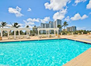 a swimming pool at the resort with palm trees and buildings at Apartment With Beautiful View in Hawaii in Honolulu