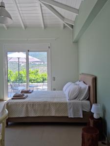 a white bedroom with a bed and a balcony at Melissafarm Guest House in Ancient Epidavros