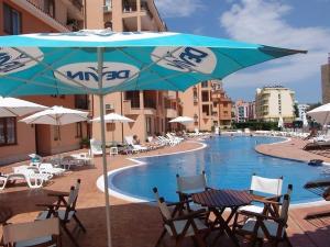 a pool with tables and chairs and an umbrella at Holidays apartment Kassandra Sunny Beach in Sunny Beach