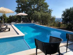 uma piscina com duas cadeiras e um guarda-sol em The View Split. Highlight with Roof-Top-Terrace and Pool em Kaštela