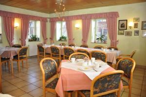 a restaurant with tables and chairs and pink curtains at Pension Lindenhof in Kromsdorf