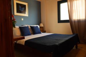 a bedroom with a bed with blue pillows and a window at Blu Casa Del Mare in Monemvasia