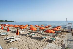 een stel parasols en stoelen op een strand bij Villaggio Turistico Le Diomedee in Vieste