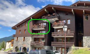 a building with a green circle on the side of it at Ruim en modern appartement super centraal gelegen aan de piste in Valmorel