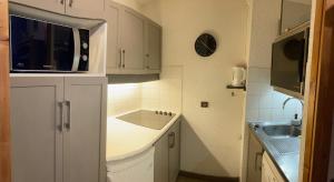 a small kitchen with white cabinets and a sink at Ruim en modern appartement super centraal gelegen aan de piste in Valmorel
