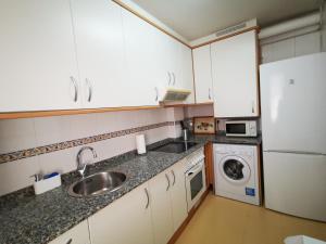 a kitchen with white cabinets and a sink and a dishwasher at Apartamento Centro Gijón in Gijón +12 photos