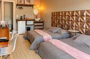 a bedroom with two beds and a kitchen with a counter at Pousada Doce Lar in Penha