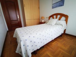 a bedroom with a bed with a white comforter at Apartamento Centro Gijón in Gijón