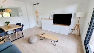 ein Wohnzimmer mit einem TV und einem Tisch in der Unterkunft Apartamento diseño con jardín privado a 100 metros del mar in Torredembarra