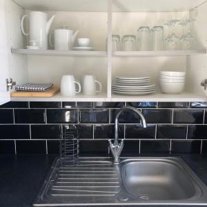 a kitchen with a sink and a shelf with dishes at 2 Bedroom, Near Station, Fast WI-FI, Free Parking! in London