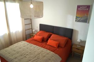 een slaapkamer met een groot bed met oranje kussens bij Maison neuve chaleureuse en Provence, terrasse in Piolenc