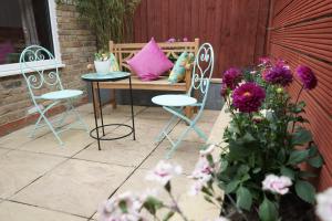 patio z 2 krzesłami i stołem z różową poduszką w obiekcie Luxury London Garden home sleep 7, 2 mins to metro w Londynie