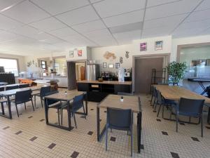 a restaurant with tables and chairs and a kitchen at Hotel Caplandes in Capbreton