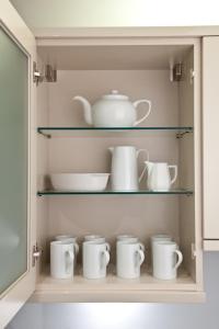 a cupboard filled with lots of white cups and dishes at Hay Retreats in Hay-on-Wye