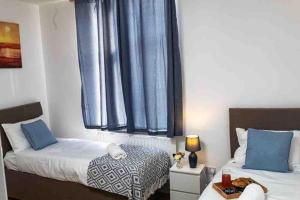 a bedroom with two beds and a window with blue curtains at Silver Apartment 2 Bed Flat Leicester City Centre in Leicester